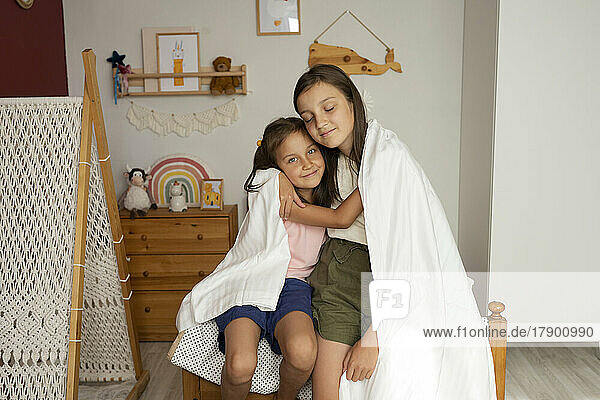 Sisters wrapped in blanket embracing each other