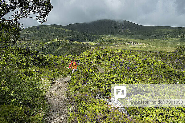 Senior woman walking amidst plants  Morro Alto and Pico da Se mountains  Flores Island  Azores  Portugal