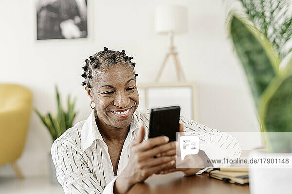 Happy woman using smart phone in living room at home