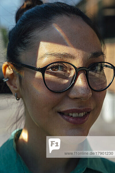 Smiling businesswoman with sunlight on face wearing eyeglasses