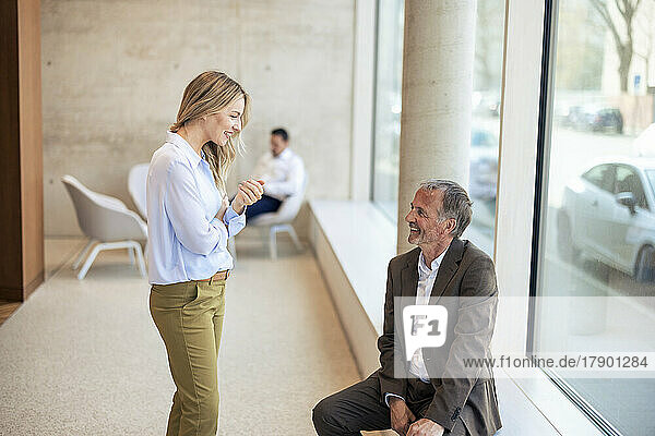 Smiling senior businessman talking with colleague in office