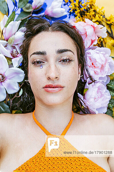 Sad woman lying on flowers with teardrop sticker