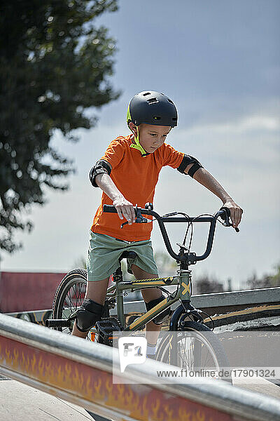 Determined boy wearing helmet riding BMX bike