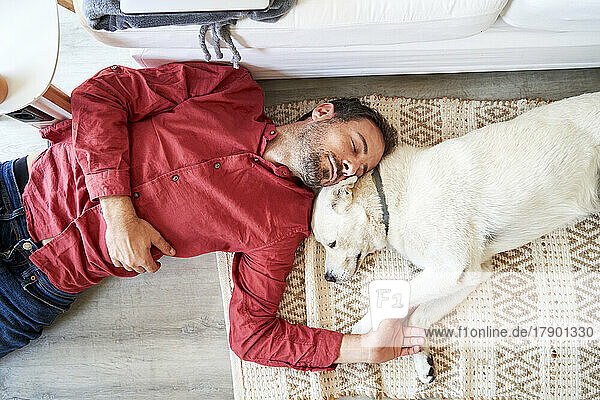 Man and dog sleeping together on carpet at home
