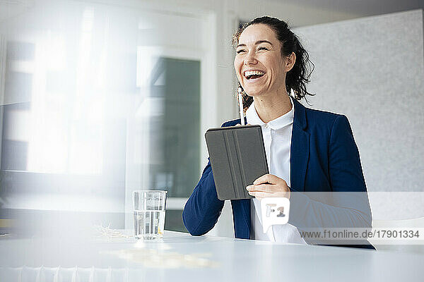Happy businesswoman holding tablet PC and digitized pen