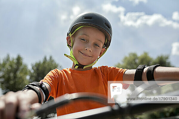Smiling boy wearing cycling helmet and protective gear