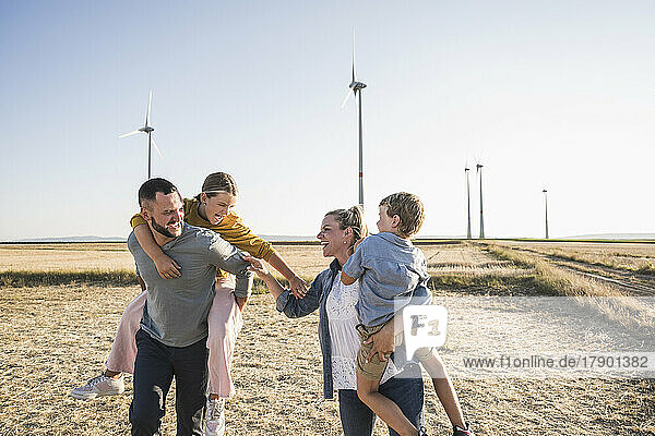 Confident family standing in wind park holding hands