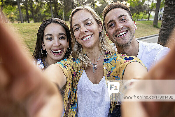 Glückliche Frau macht Selfie mit Freunden im Park