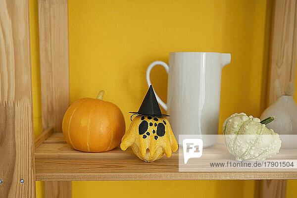 Painted pumpkin with witch's hat on shelf