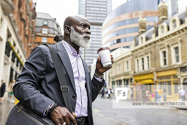 Thoughtful businessman having coffee on city street