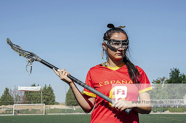 Young player holding lacrosse stick wearing protective eyewear