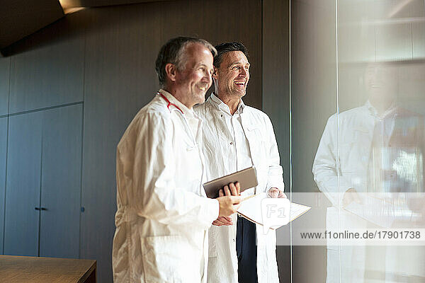 Happy doctors looking out of glass wall in hospital