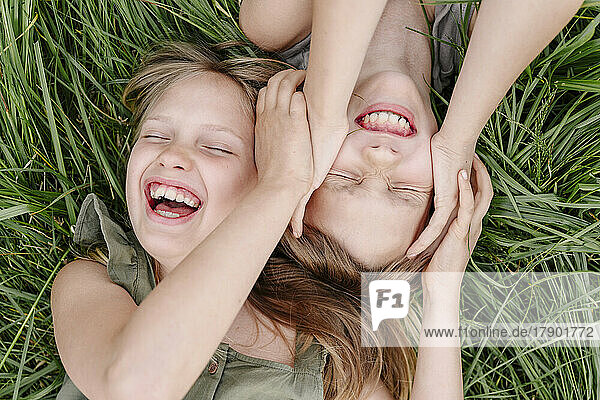 Brother and sister having fun together lying on grass