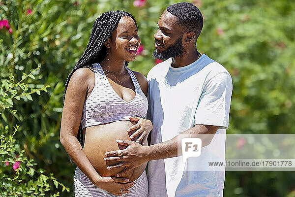 Romantic man looking at pregnant girlfriend on sunny day