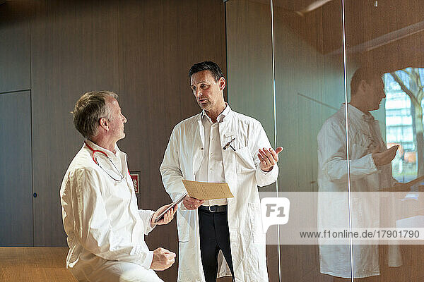 Healthcare workers wearing lab coat discussing with each other in hospital