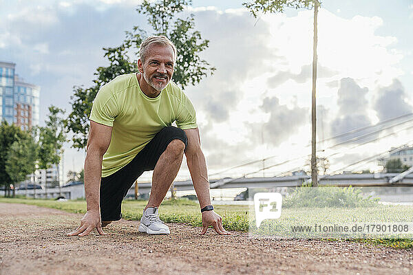 Smiling mature man in starting position at park