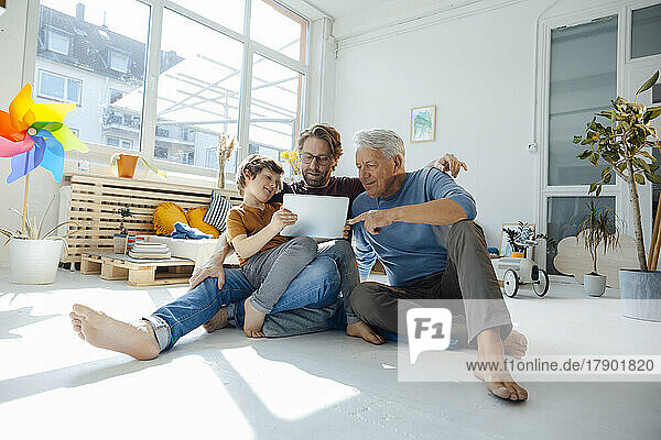 Boy sharing tablet PC with father and grandfather at home