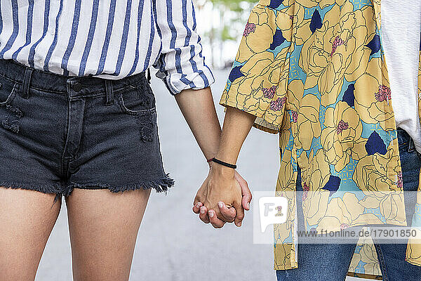 Young women holding hands at park