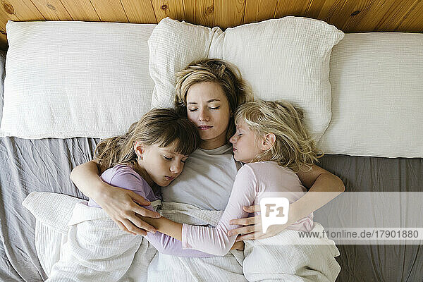 Mutter mit Töchtern  die zu Hause im Bett schlafen