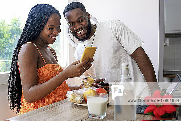 Happy couple sharing smart phone at home