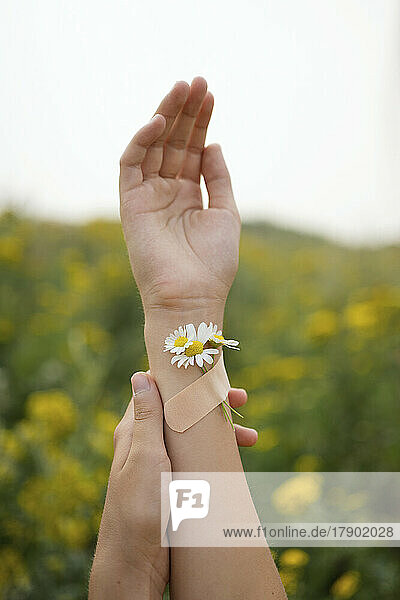 Girl with flowers attached on hand by adhesive bandage