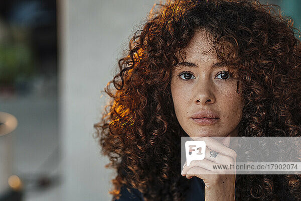 Curly haired beautiful young woman with hand on chin