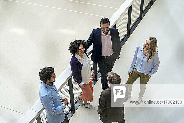Multiracial business colleagues discussing together in office corridor
