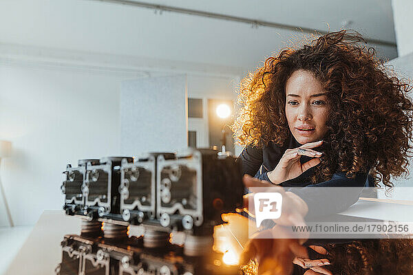 Young engineer with curly hair analyzing lighting equipment at desk