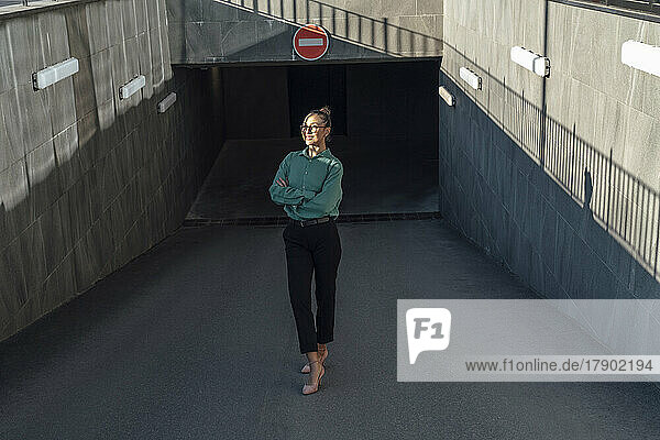 Smiling businesswoman standing with arms crossed at parking garage