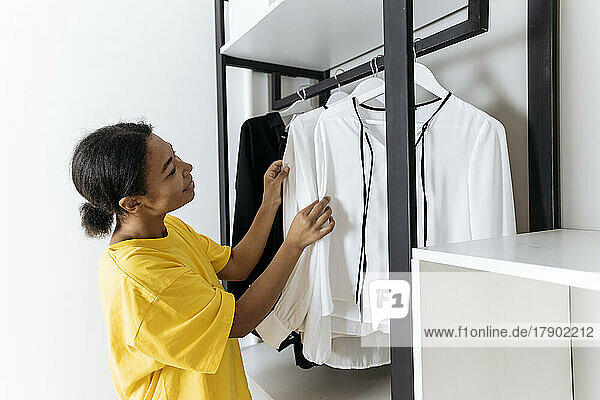 Woman looks at choosing top in closet