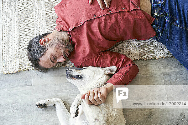 Man lying on floor with dog at home