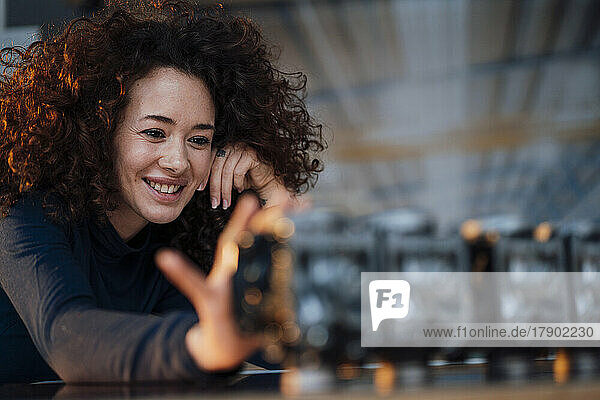 Smiling young engineer with curly hair examining lighting equipment