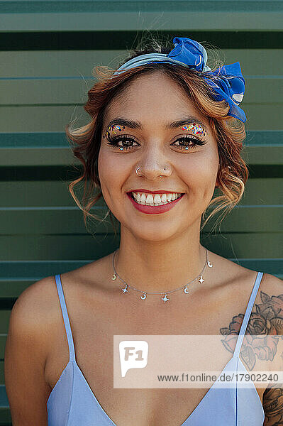 Lächelnde Frau mit Stirnband und glitzerndem Augen-Make-up