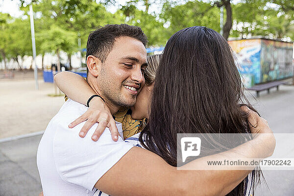 Smiling young man hugging friends at park