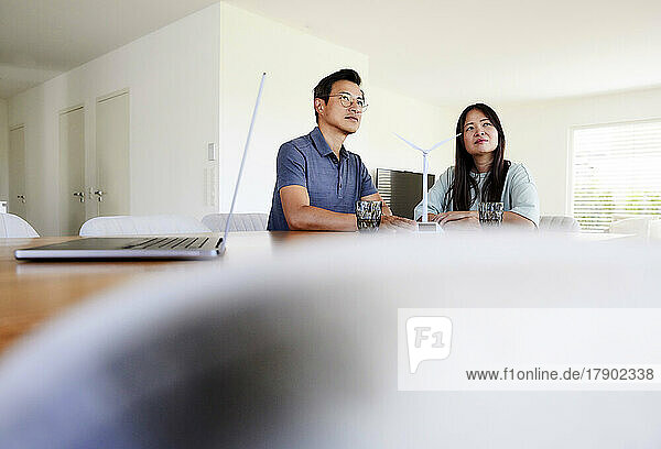 Thoughtful freelancers with wind turbine model sitting at home