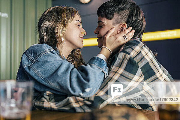 Loving young lesbian couple sitting at table in restaurant