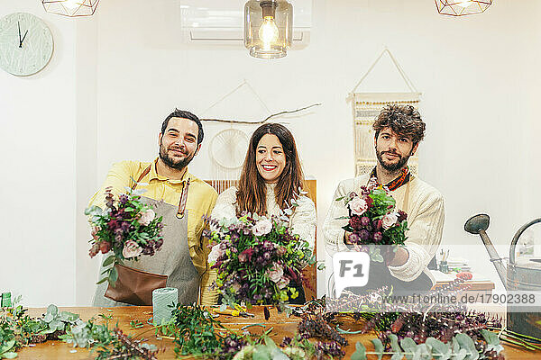 Smiling florists holding bouquets standing at floral shop