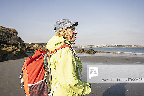 Lächelnde ältere Frau am Strand an einem sonnigen Tag