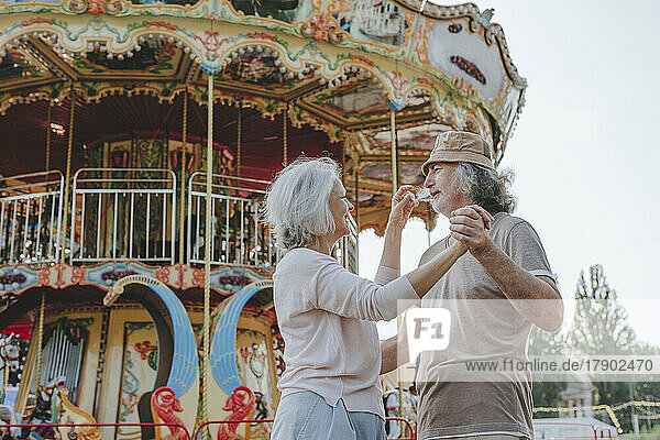 Smiling couple dancing together in front of carousel