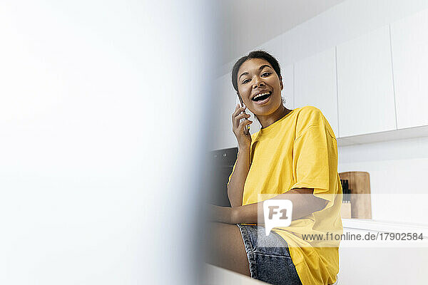 Happy woman talking on the phone in the kitchen