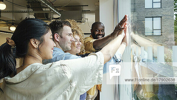 Group of business people looking out of window stacking hands