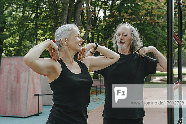 Smiling couple doing warm up exercise in park
