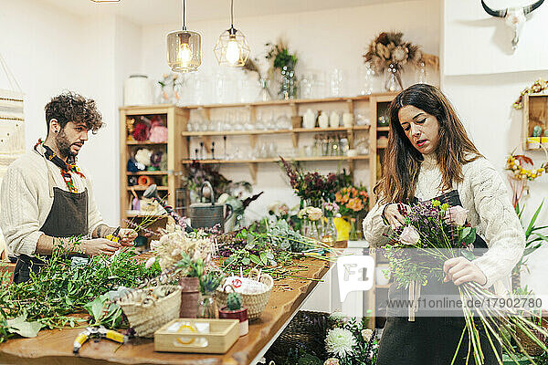 Saleswoman making bouquet by colleague at flower shop