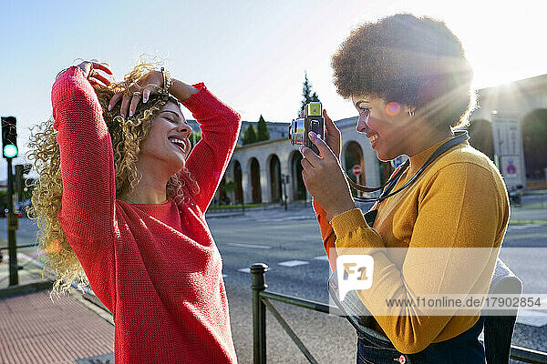 Smiling woman taking pictures of girlfriend through camera