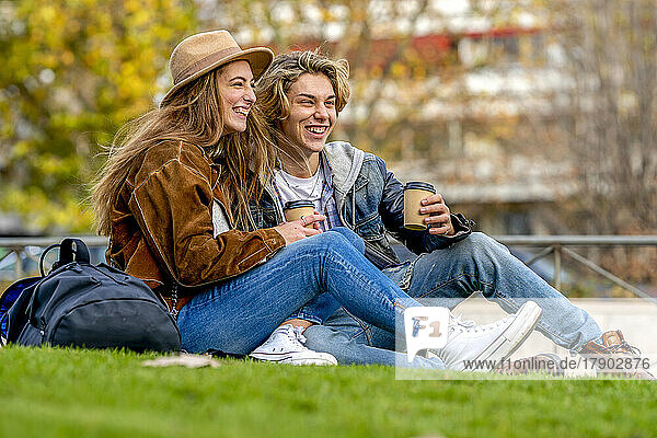 Happy tourists with disposable cups sitting in park