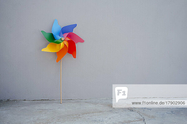 Multi colored pinwheel toy in front of gray wall