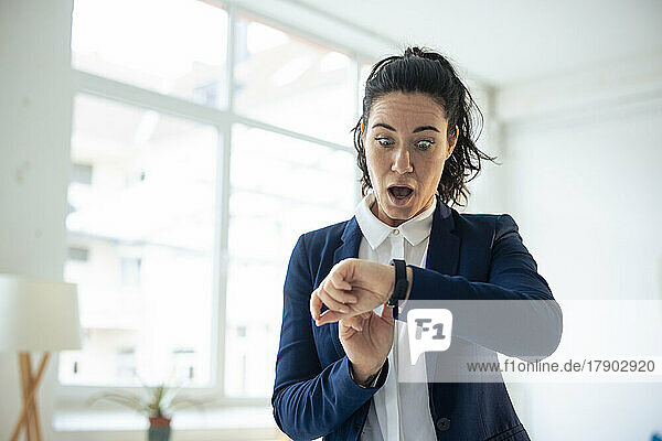 Shocked businesswoman looking at smart watch