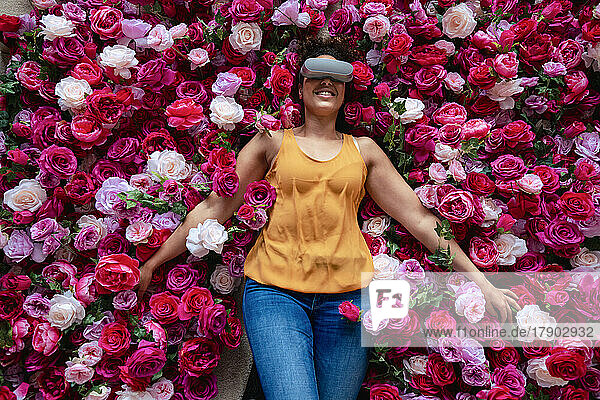 Mature woman wearing VR glasses lying on flowers