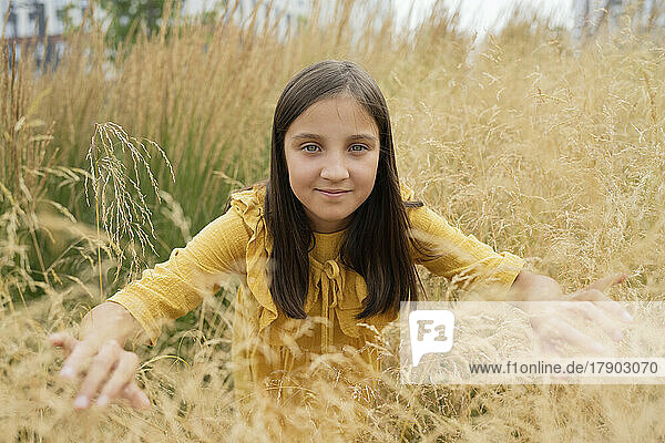 Smiling pre-adolescent girl amidst grass in field