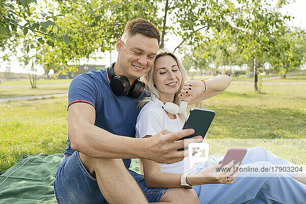 Young man and woman talking on video call through smart phone in park